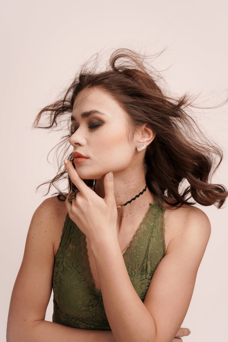 Elegant woman in green lace top posing with eyes closed in artistic portrait photography